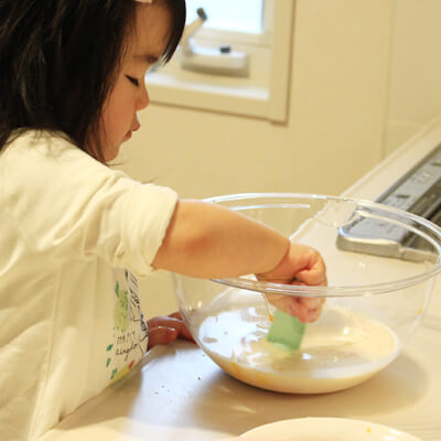 パンケーキ作りのお手伝いをする1歳児