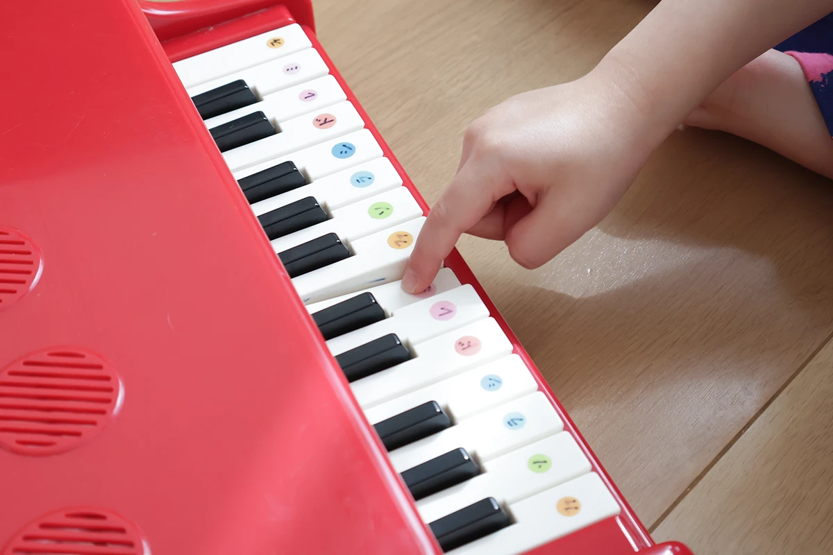 カワイのミニピアノを引いている3歳児