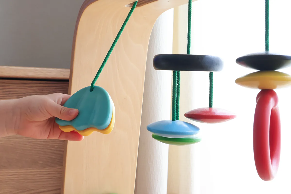 IKEAの木製ベビージムのおもちゃを手に取る赤ちゃん