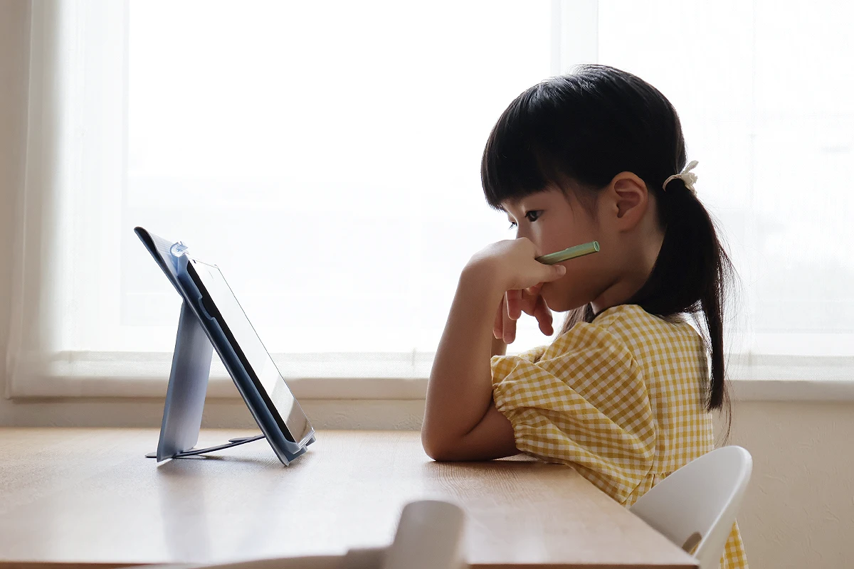 リビングでタブレット学習する子ども