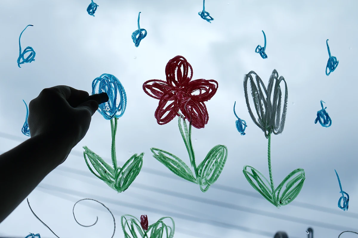 窓に描けるクレヨン・ペンで雨の日アートを楽しむ様子